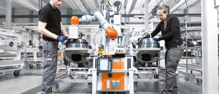 Collaborative robot, or cobot, id operated by a men and a women at the factory premises.