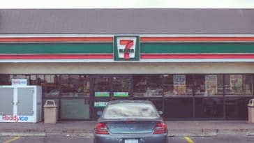 A blue car in front of a 7-Eleven store